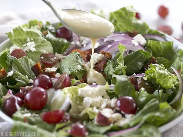 Spoonful of dressing being poured onto Grape Feta and Bacon Salad 