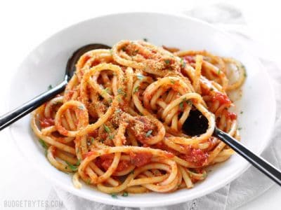 Pasta with butter tomato sauce and toasted breadcrumbs with utensils.