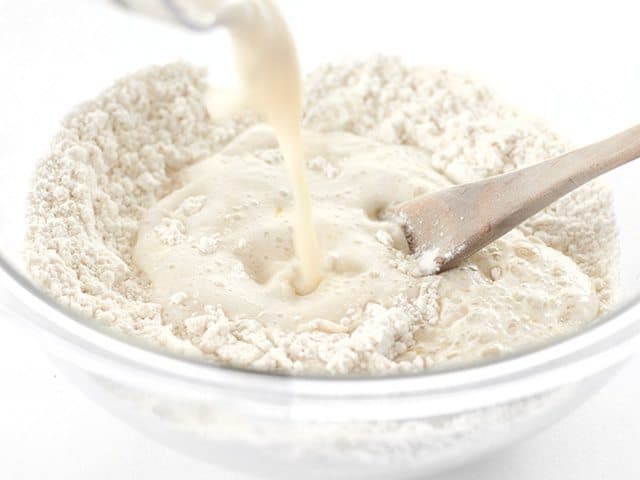 Yeasty water being poured into a bowl of flour