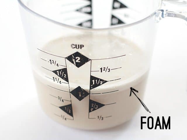 Yeast dissolved in water in a measuring cup, with a foamy layer on top