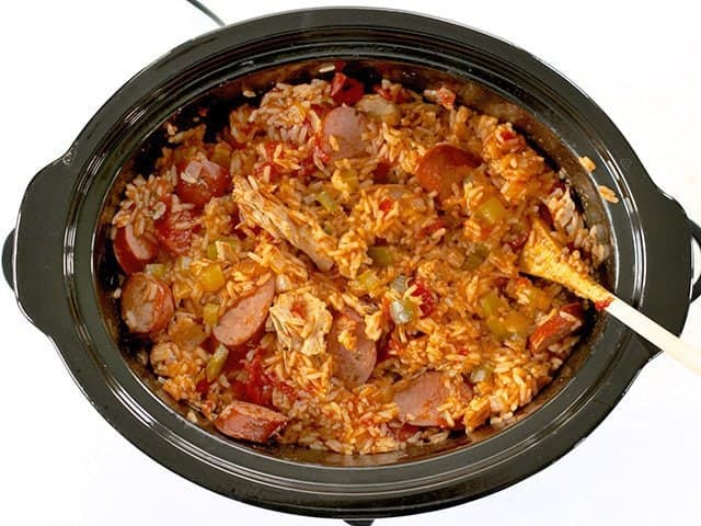 Stirring dish with wooden spoon in slow cooker 