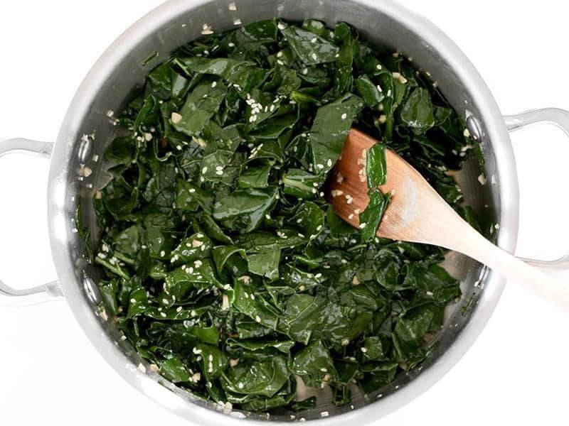 Sautéed kale in a pot with soy sauce and sesame seeds