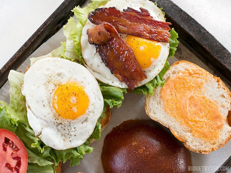 Brown Sugar Bacon Breakfast Sandwiches on a baking sheet being assembled