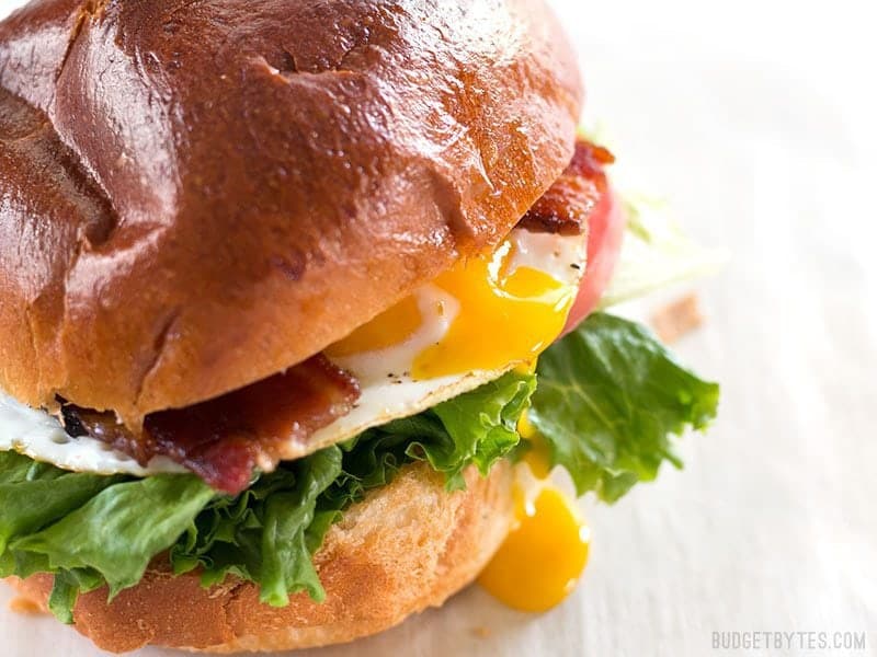 Close up of a runny yolk dripping down the side of a Brown Sugar Bacon Breakfast Sandwiches 