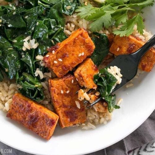 Chili garlic tofu bowl garnished with herbs.