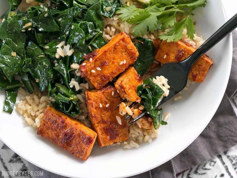 Chili garlic tofu bowl garnished with herbs.