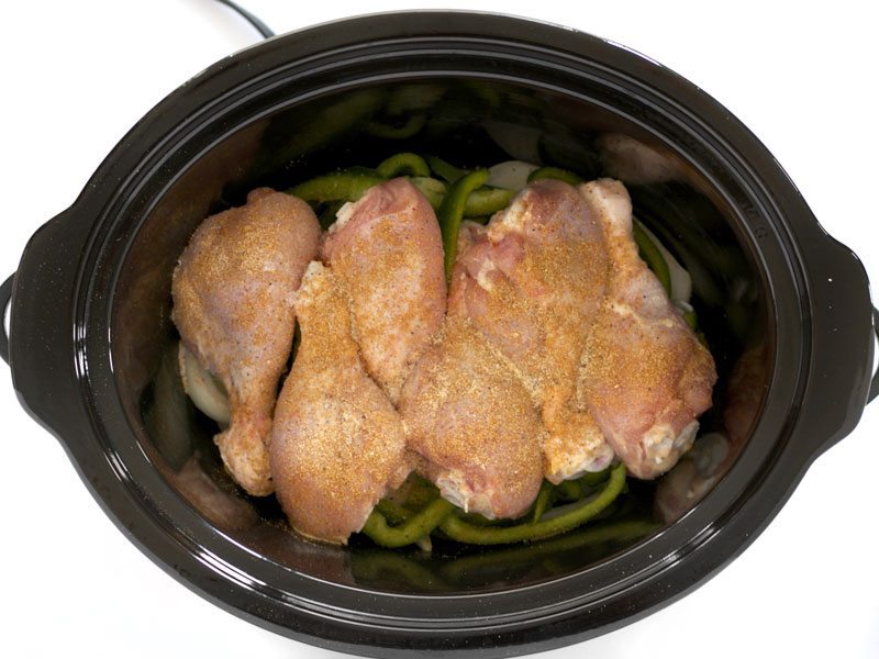 Seasoned Drumsticks in the Slow Cooker on top of the onions and peppers