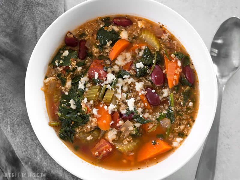 A bowl full of Garden Vegetable Quinoa Soup topped with a little crumbled queso fresco