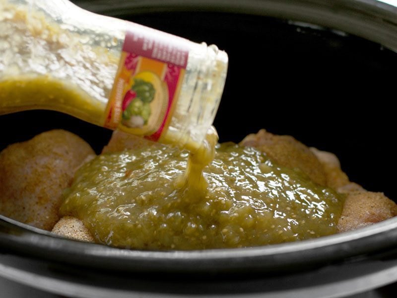 Green salsa being poured on top of the chicken