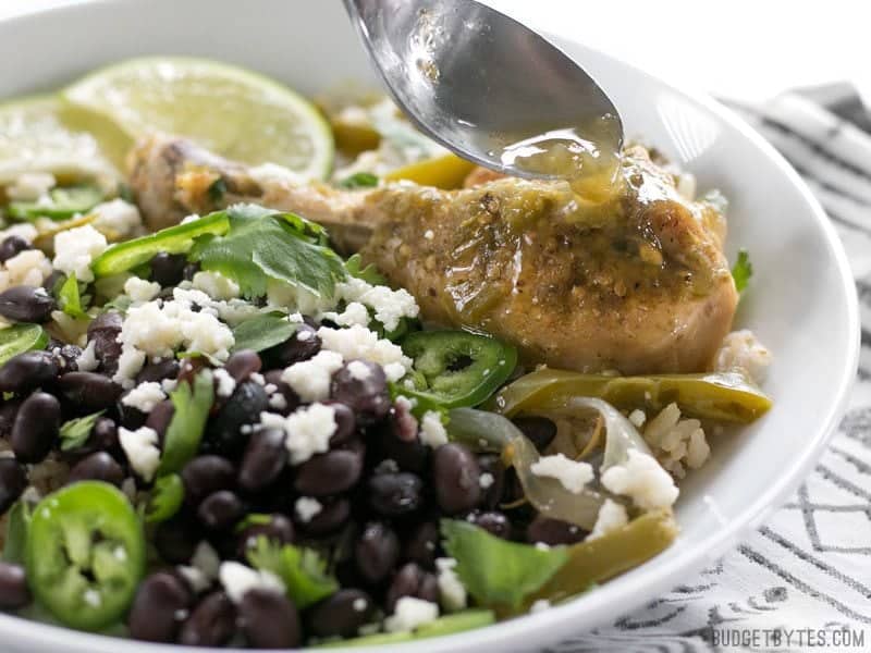 Green sauce being spooned onto a piece of Slow Cooker Salsa Verde Chicken in the bowl