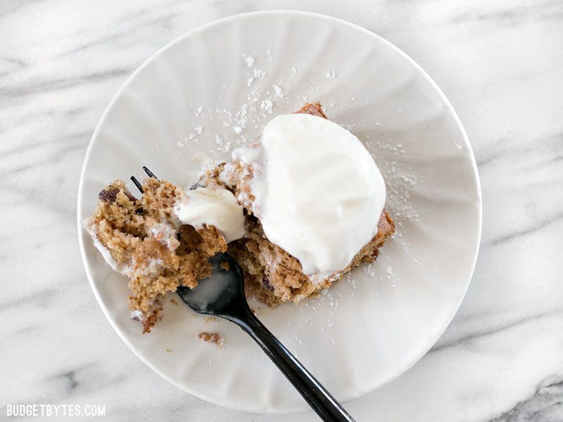 Overhead view of one slice of Applesauce Cake with a scoop of ice cream on top, being eaten with a fork.