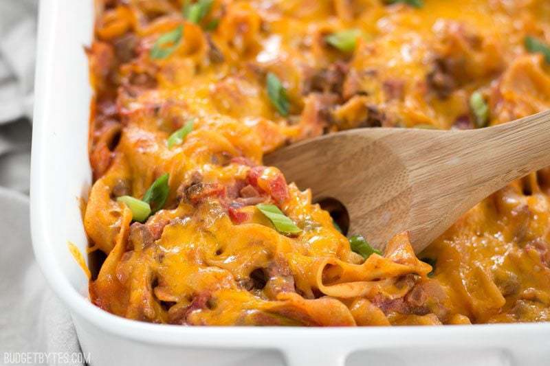 Close up of Beef & Mushroom Country Casserole being scooped with a wooden spoon out of the corner of the dish