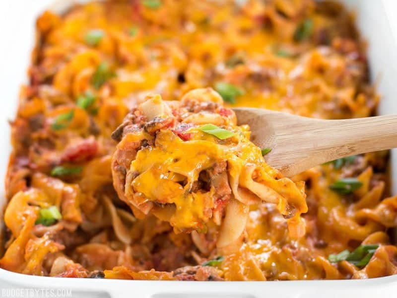 Close up of Beef & Mushroom Country Casserole being scooped out of the casserole dish with a wooden spoon.