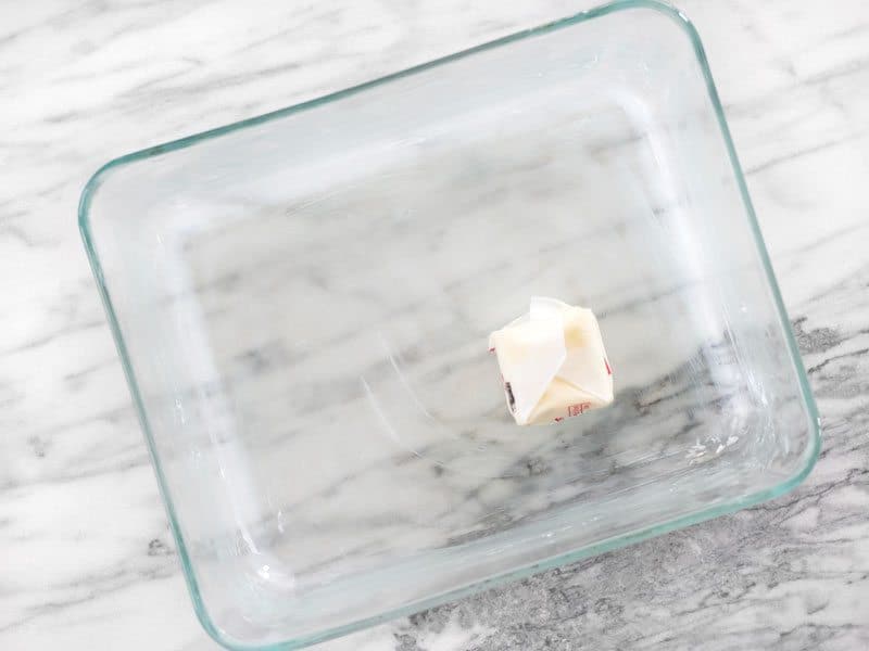 Glass dish being greased with a piece of butter