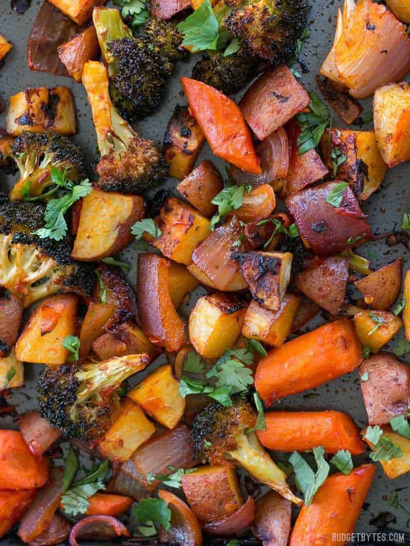 Close up of Harissa Roasted Vegetables garnished with cilantro on a sheet pan.