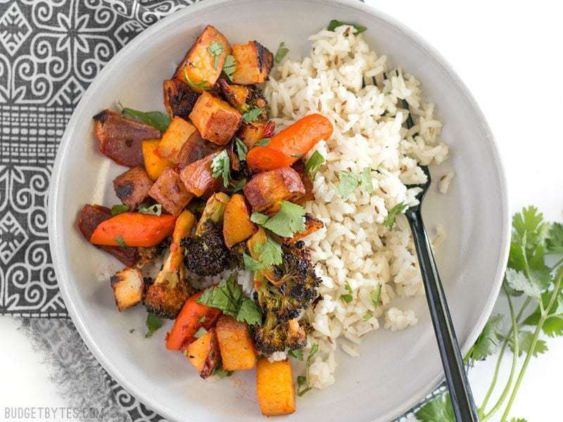 Harissa Roasted Vegetables in a bowl with cumin rice, garnished with cilantro