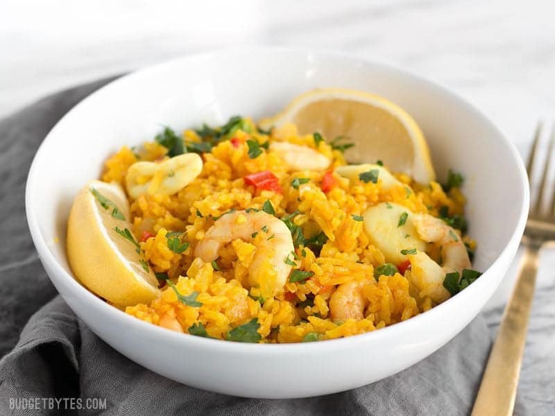 Front view of a bowl of Seafood Rice Skillet, gold fork on the side