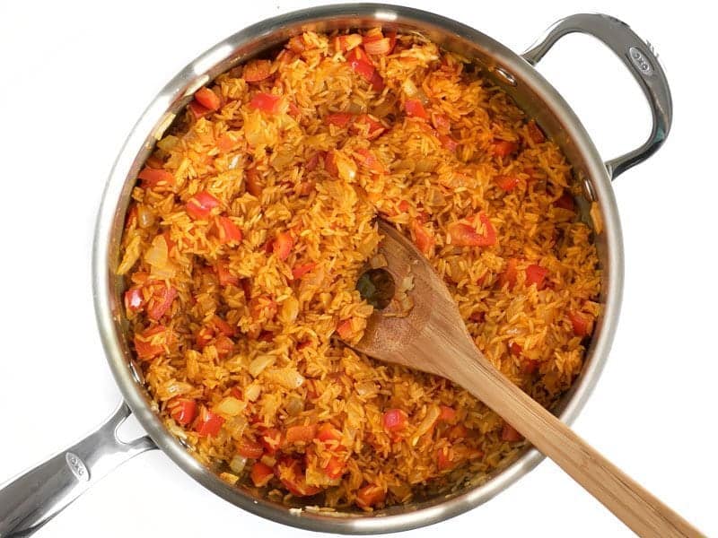 Stirred Rice and Spices in skillet with wooden spoon