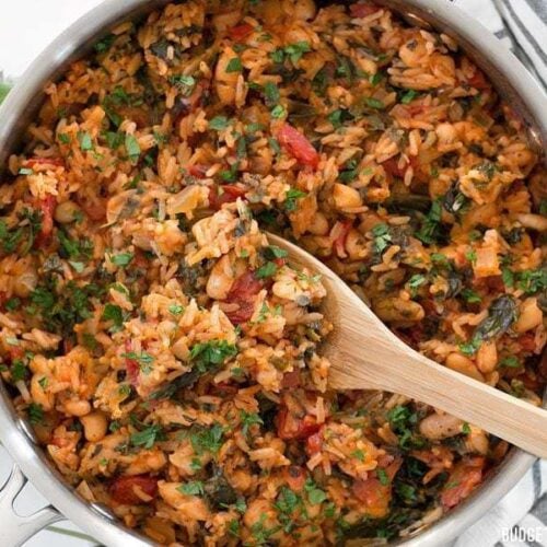 Tomato herb rice with beans and spinach in a saucepan.