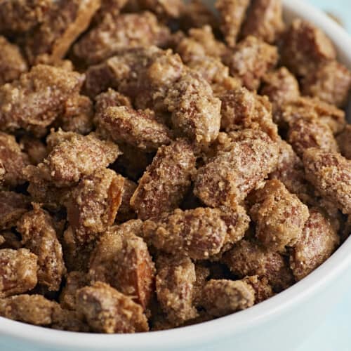 Close up side view of candied almonds in a bowl.