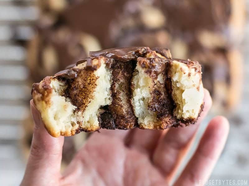 Close up of a hand holding one chocolate cinnamon bun that has been torn in half so the inside is visible