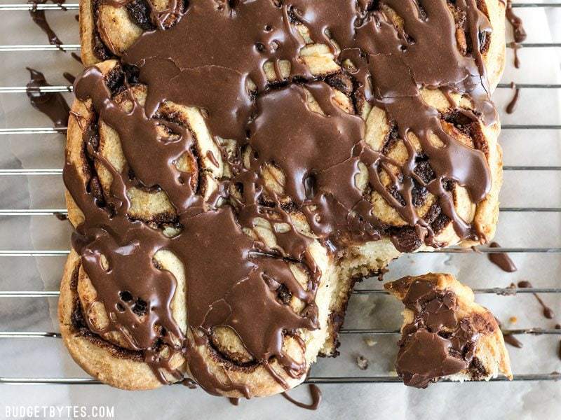 chocolate cinnamon buns with chocolate icing, viewed from above, on a wire cooling rack