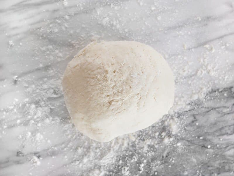 Cohesive Biscuit Dough in a ball on a floured marble surface