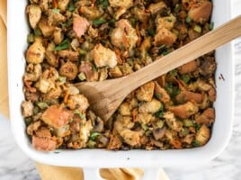 Overhead view of vegetarian stuffing in the casserole dish with a wooden spoon.