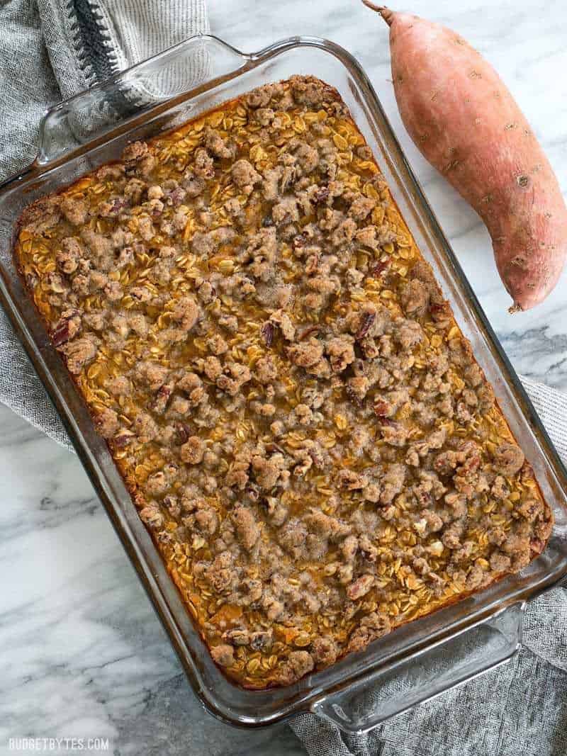 A full casserole dish of Sweet Potato Casserole Baked Oatmeal with a whole sweet potato on the side.