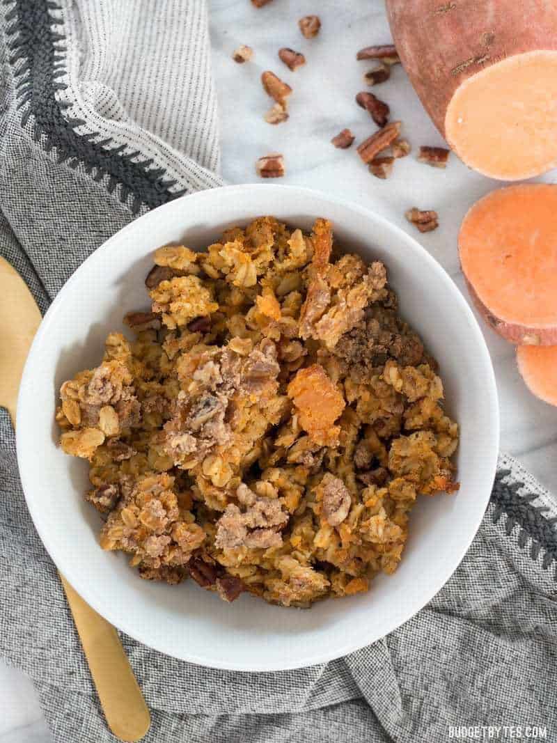 A bowl full of Sweet Potato Casserole Baked Oatmeal with a sliced fresh sweet potato on the side.