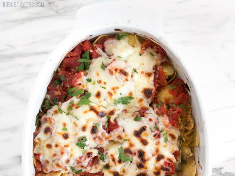 Overhead shot of half of the Baked Chicken with Artichokes and Tomatoes in the casserole dish