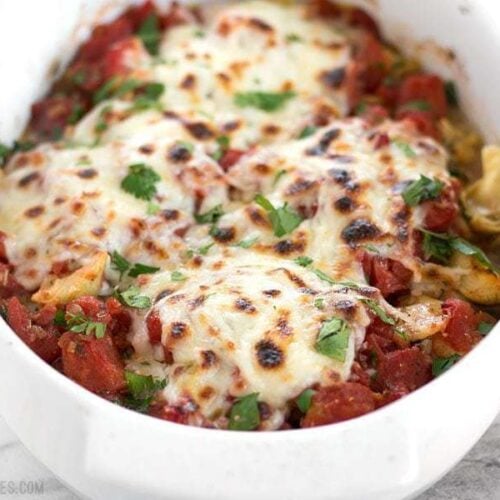 Baked chicken with artichokes and tomatoes on a plate.