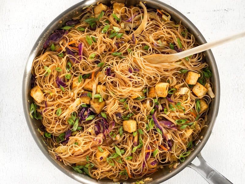 Finished Singapore Noodles with Crispy Tofu in the skillet with a wooden pasta fork