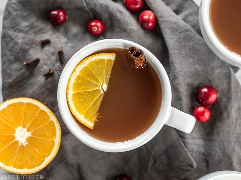 Close up of one mug full of Slow Cooker Spiced Cranberry Apple Cider with an orange slice and cinnamon stick