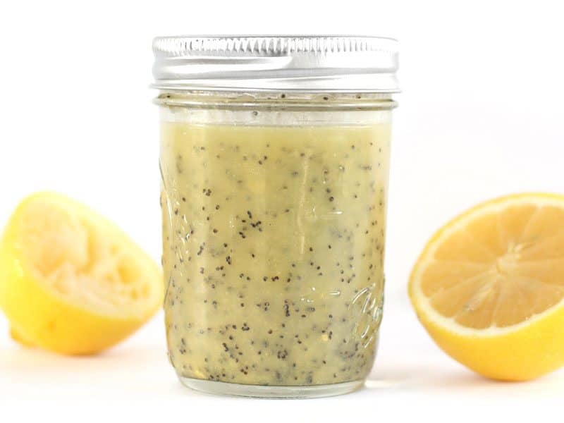 Lemon Poppy Seed Dressing in a mason jar with lemon halves in the background