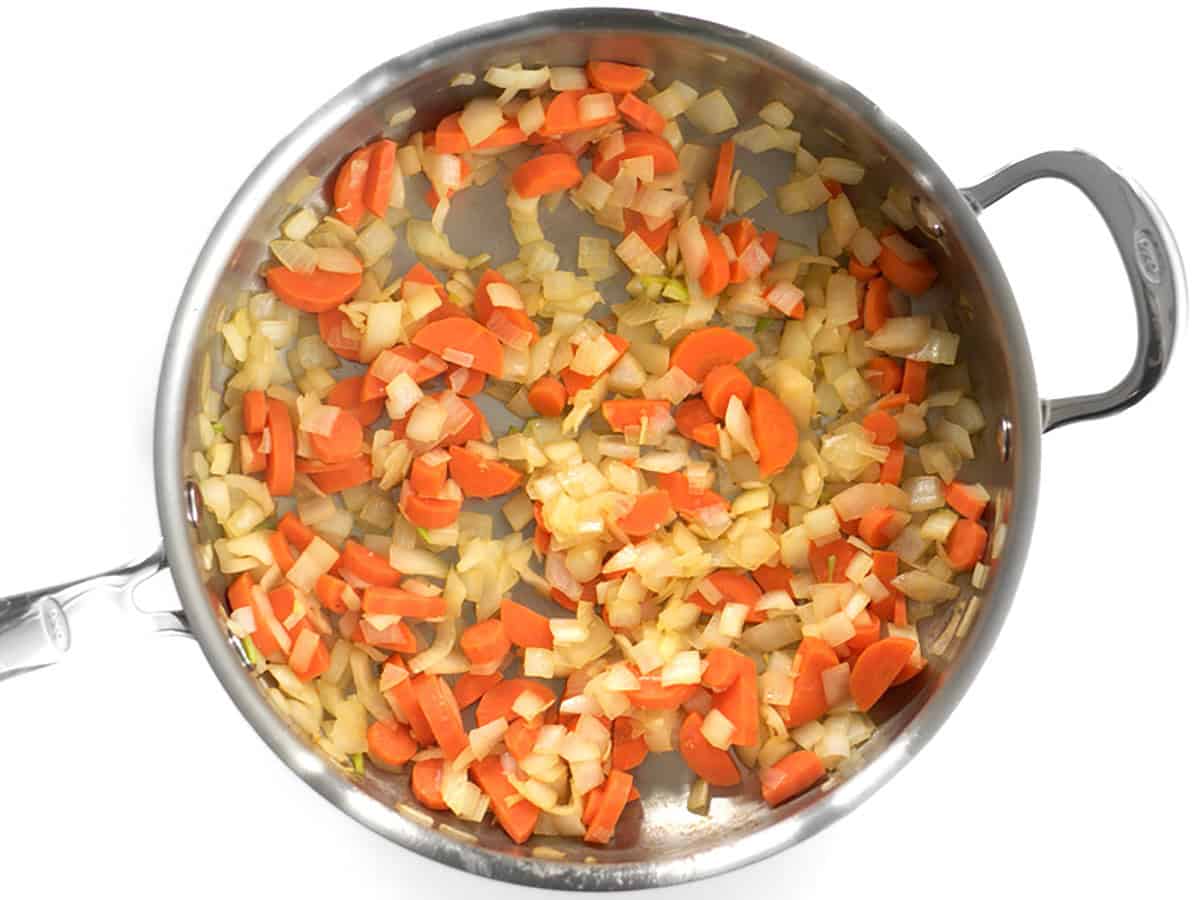 Sautéed carrots and onions in a skillet.