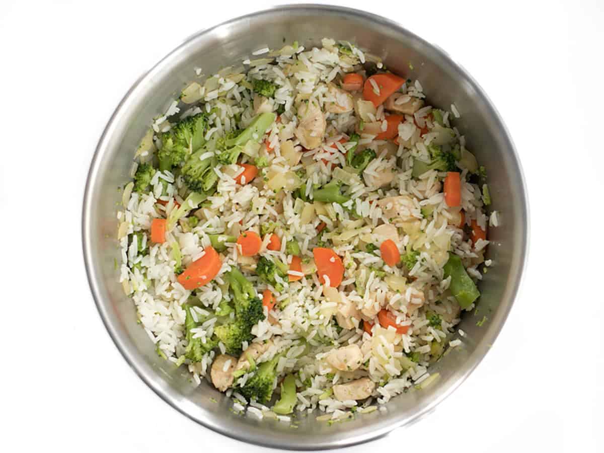 Broccoli and rice in a mixing bowl with sautéed vegetables.