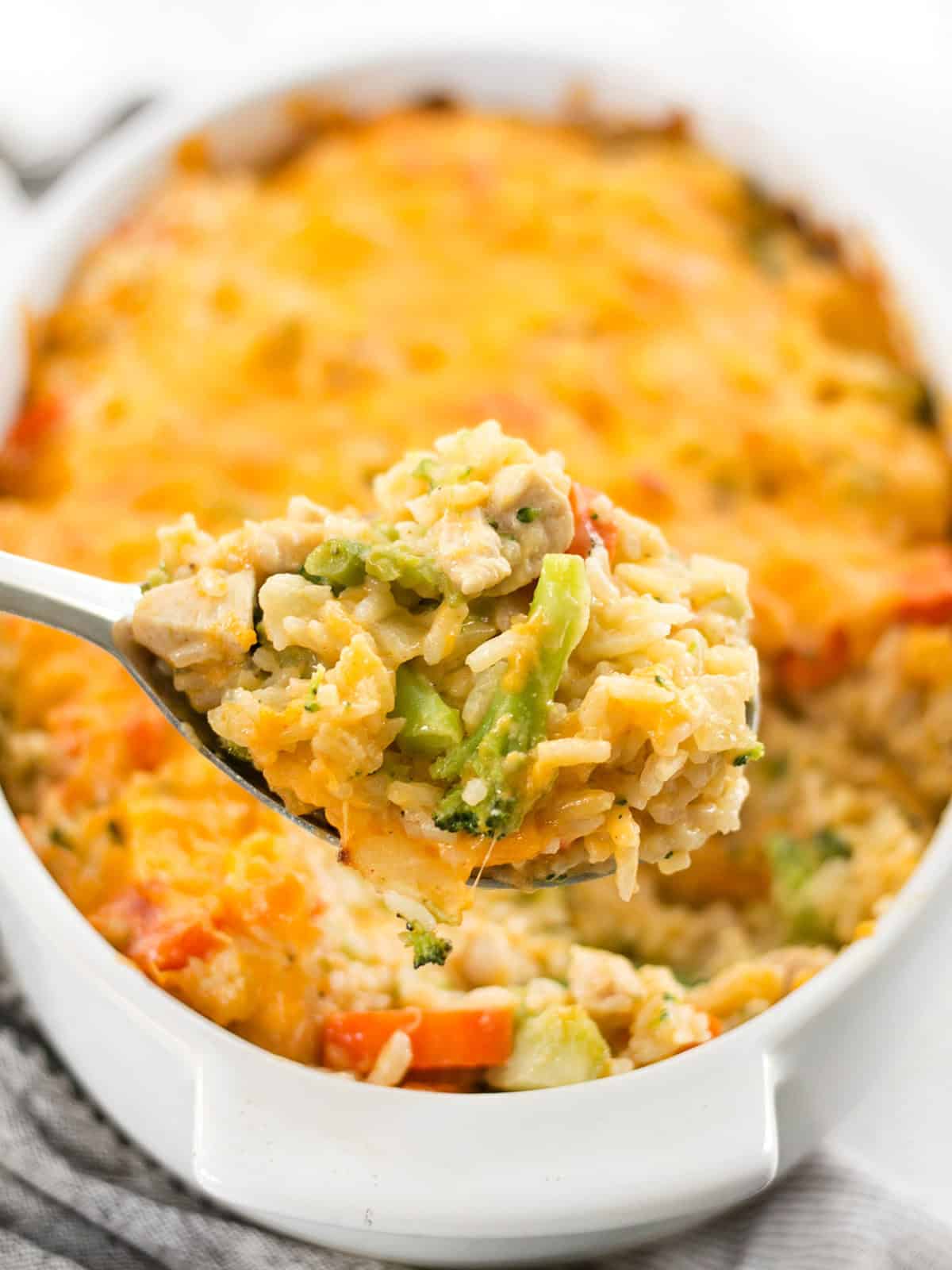 Close up of a scoop of chicken and rice casserole being lifted from the baking dish.