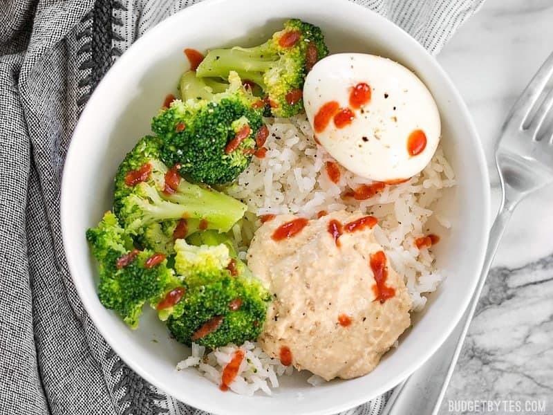 Overhead shot of a freshly made Hummus Breakfast Bowl with sriracha drizzled over top