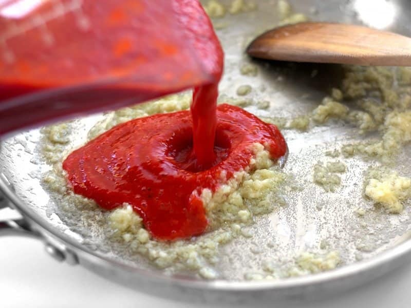 Pour pureed Roasted Red Peppers into the skillet with garlic and butter