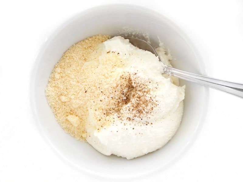 Ricotta, Parmesan, and pepper being stirred together in a bowl