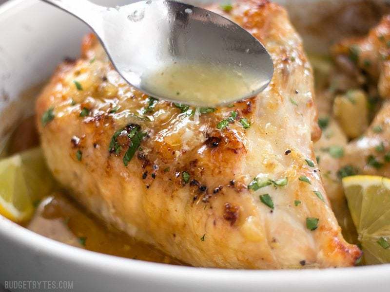 Close up of pan juices being spooned over Lemon Garlic Roasted Chicken 