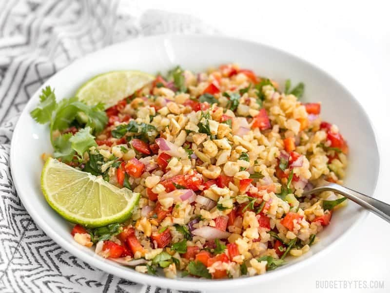 Side view of a bowl of Peanut Lime Cauliflower Salad on a patterned napkin