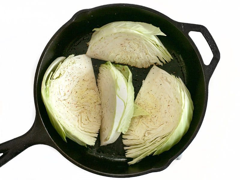 Raw cabbage wedges in a cast iron skillet