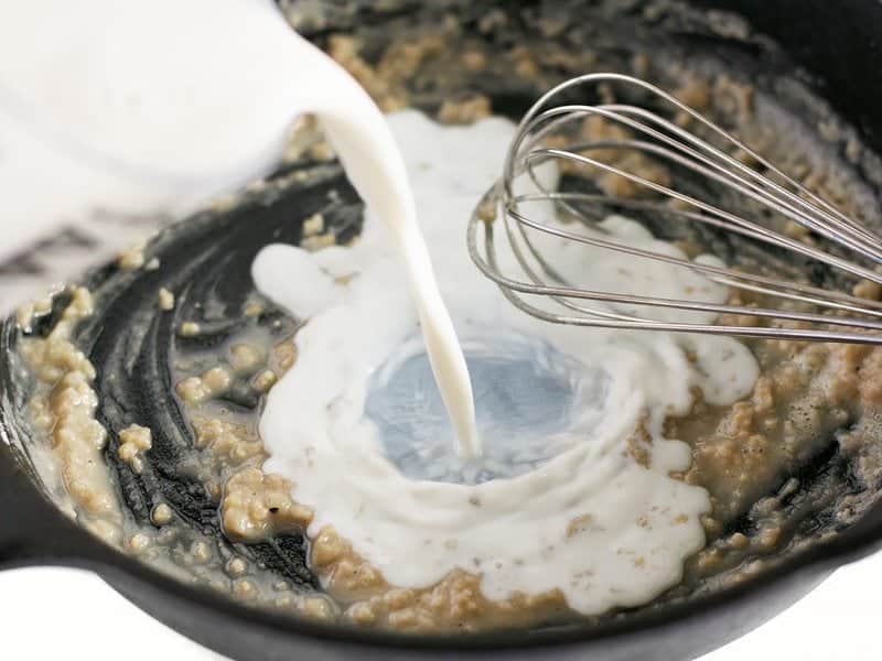 Milk being whisked into butter, flour, and garlic