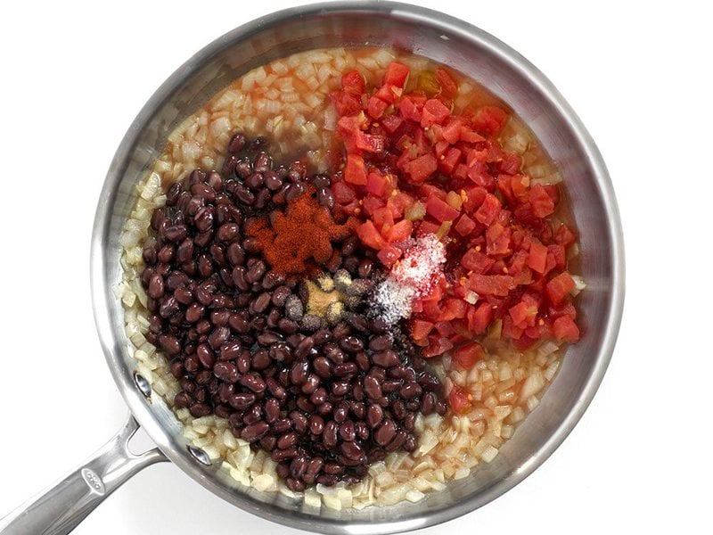 Beans, tomatoes, and seasonings added to skillet with onions