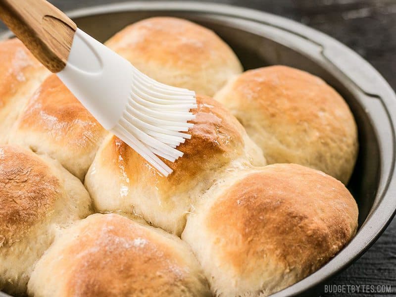 Melted butter being brushed onto the Buttermilk Pull-Apart Rolls with a silicone brush