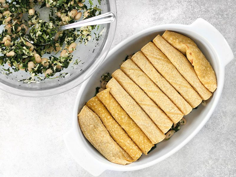 Stuffed and rolled spinach white bean enchiladas in casserole dish