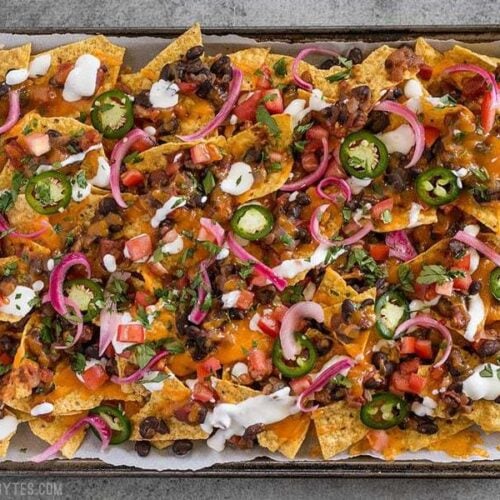 For the perfect Spicy Baked Black Bean Nachos, layer your chips and toppings for the perfect chip-to-topping ratio. BudgetBytes.com