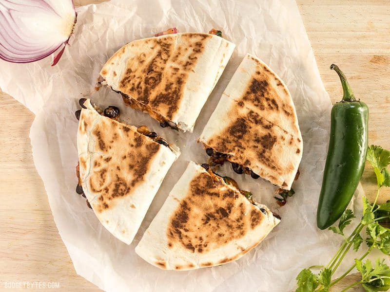 A sliced Ultimate BBQ Chicken Quesadilla on a piece of parchment paper